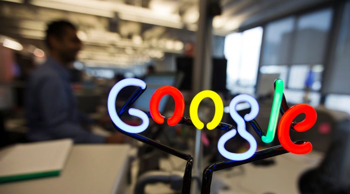 A neon Google logo is seen as employees work at the new Google office in Toronto